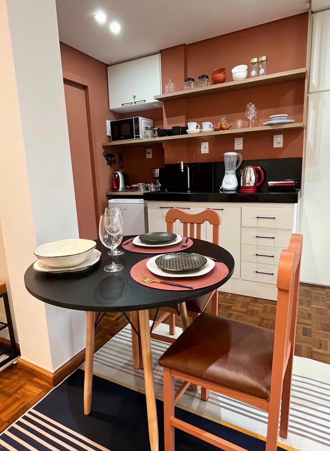 Mesa posta com vinho e cozinha ao fundo