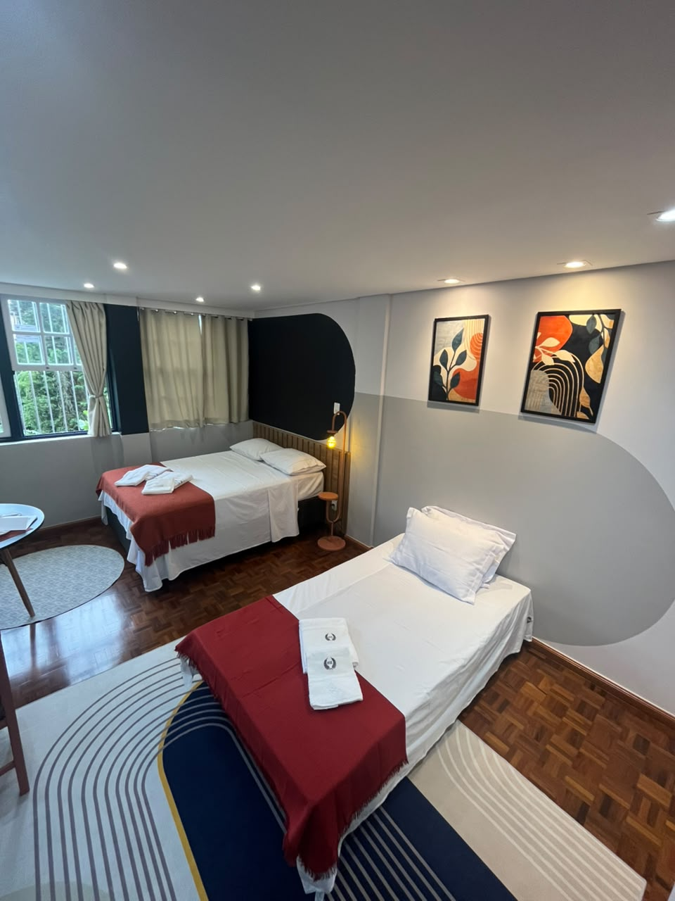 Suíte Horto I com cama de casal e cama de solteiro junto à janela