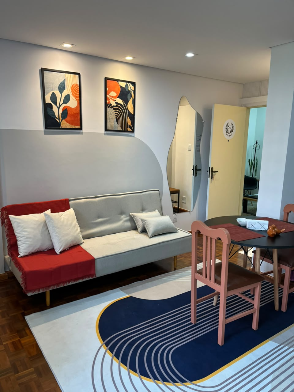 Sala de estar da Suíte Horto I com sofá-cama, quadros e mesa de jantar